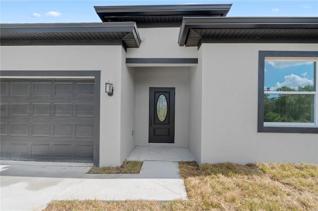 entrance to property with driveway, an attached garage, and stucco siding