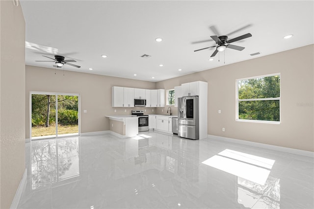 kitchen featuring open floor plan, stainless steel appliances, light countertops, and white cabinets