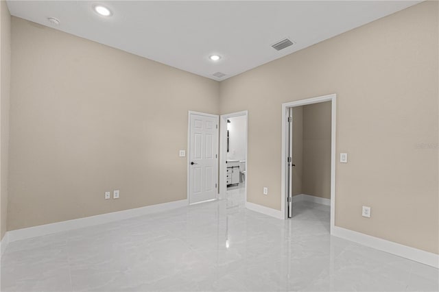 unfurnished bedroom with marble finish floor, visible vents, a spacious closet, and baseboards