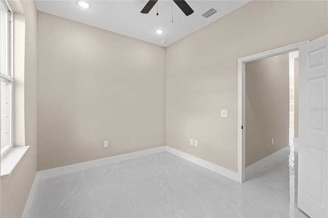 empty room with marble finish floor, a healthy amount of sunlight, visible vents, and baseboards