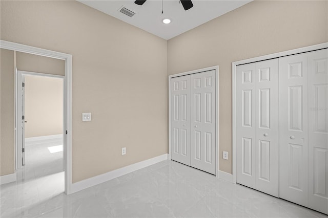 unfurnished bedroom featuring multiple closets, marble finish floor, visible vents, and baseboards