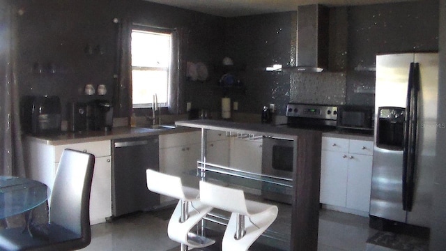 kitchen with sink, white cabinetry, tasteful backsplash, stainless steel appliances, and wall chimney range hood