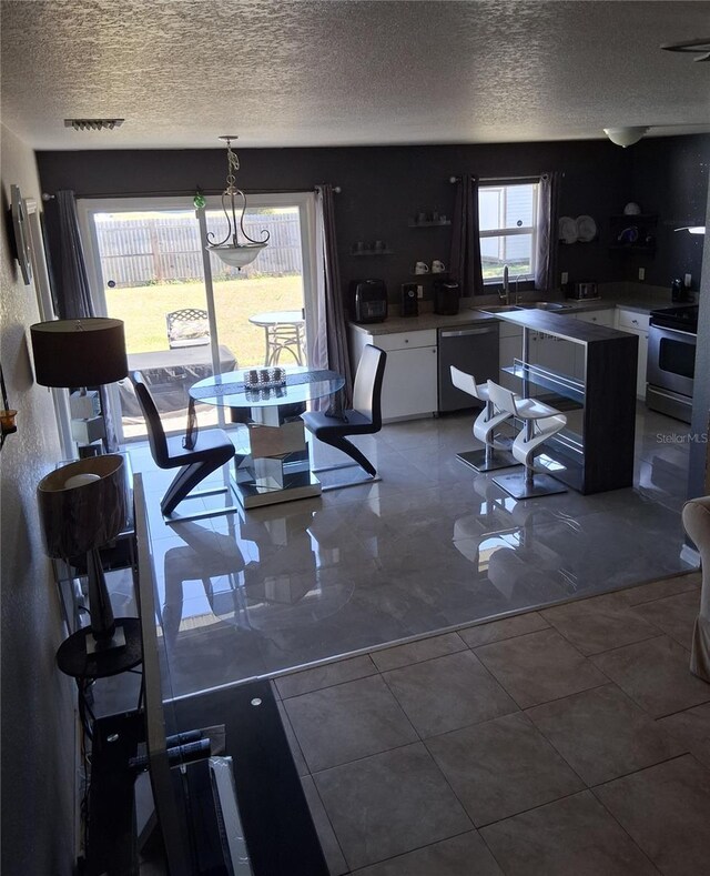 3380 Maple Ter, Port Charlotte, FL 33952 - kitchen with dishwashing machine, an inviting chandelier, a textured ceiling, stainless steel electric stove, and white cabinets