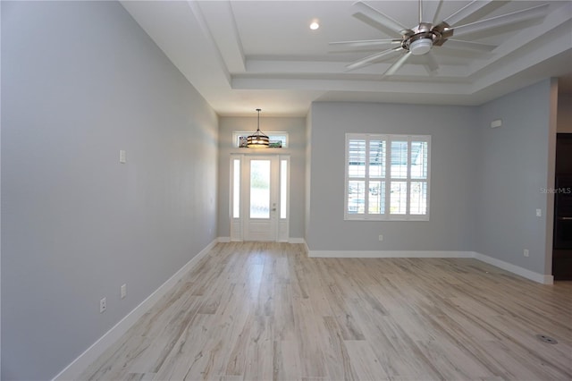 entrance foyer featuring ceiling fan, a raised ceiling, and light hardwood / wood-style flooring