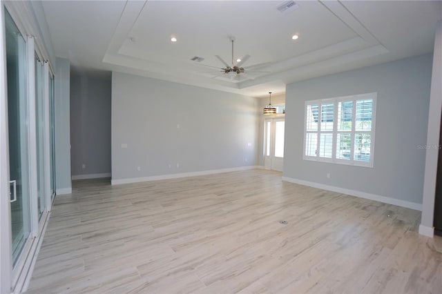 empty room featuring a tray ceiling, light hardwood / wood-style flooring, and ceiling fan