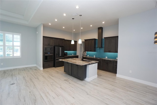 kitchen with pendant lighting, sink, a kitchen island with sink, black appliances, and wall chimney exhaust hood