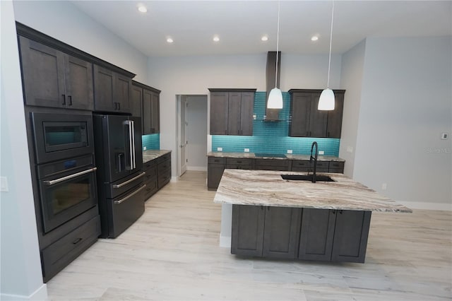 kitchen featuring pendant lighting, an island with sink, sink, black appliances, and wall chimney exhaust hood