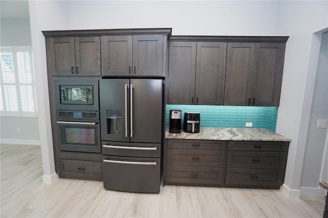 kitchen featuring dark brown cabinets, light stone countertops, and appliances with stainless steel finishes