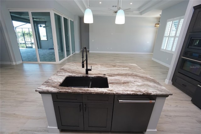 kitchen with pendant lighting, sink, light stone counters, and wall oven