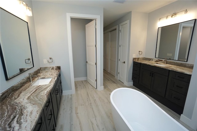 bathroom with hardwood / wood-style flooring, vanity, and a bathing tub