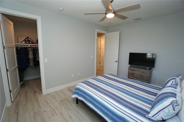 bedroom with a spacious closet, a closet, ceiling fan, and light wood-type flooring