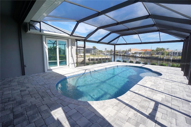 view of pool featuring a patio, a water view, and glass enclosure