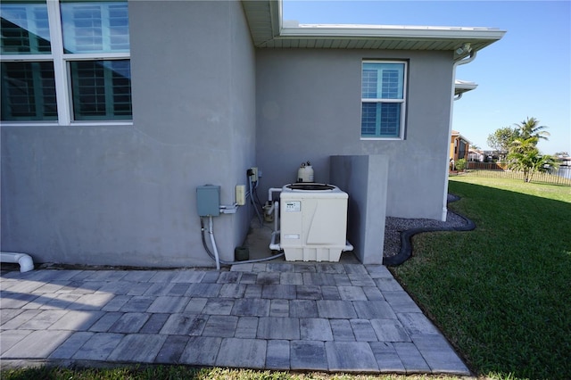 view of side of home with cooling unit, a patio area, and a lawn