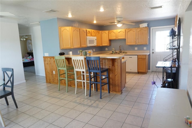 kitchen with sink, a breakfast bar area, light brown cabinets, kitchen peninsula, and white appliances