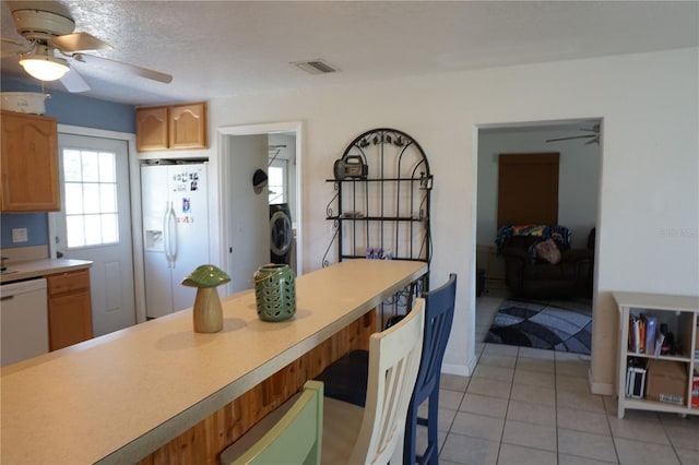 kitchen featuring ceiling fan, washer / dryer, light tile patterned floors, and white appliances