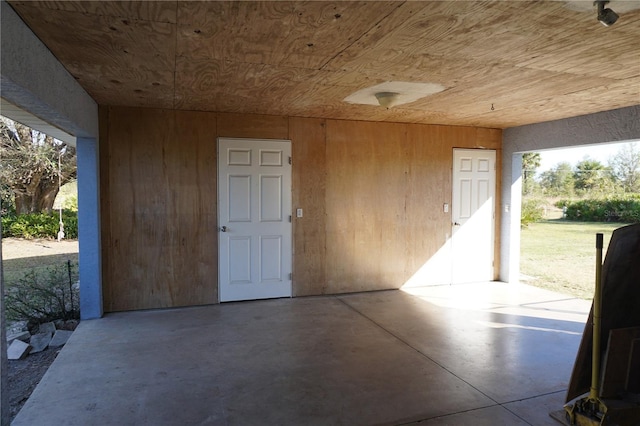 garage featuring wooden ceiling and wood walls