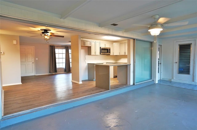 kitchen with white cabinetry, a kitchen island, beamed ceiling, ceiling fan, and backsplash