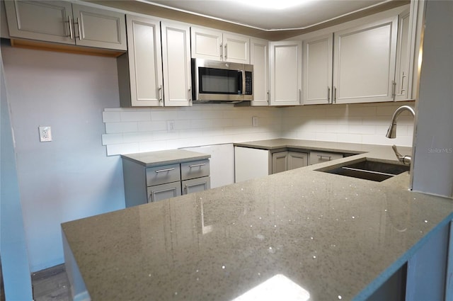 kitchen featuring tasteful backsplash, sink, and stone counters