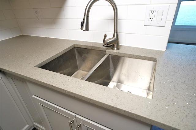 interior details with tasteful backsplash, light stone countertops, and sink