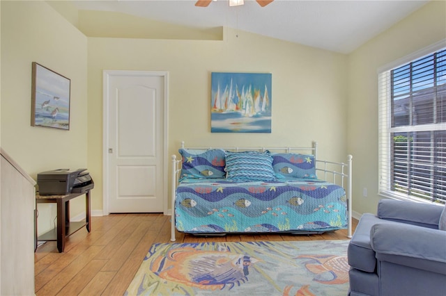 bedroom with ceiling fan, vaulted ceiling, multiple windows, and light wood-type flooring