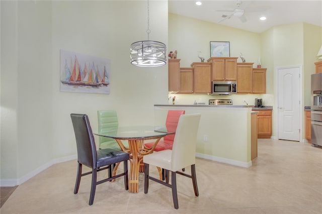 dining area with ceiling fan with notable chandelier, high vaulted ceiling, and light tile patterned flooring