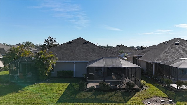 rear view of property featuring a yard and a lanai