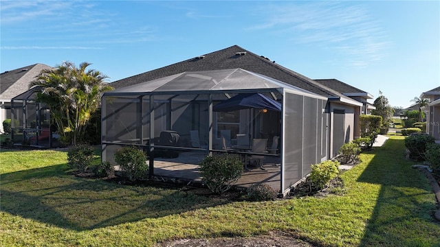 rear view of property featuring a patio area, glass enclosure, and a lawn