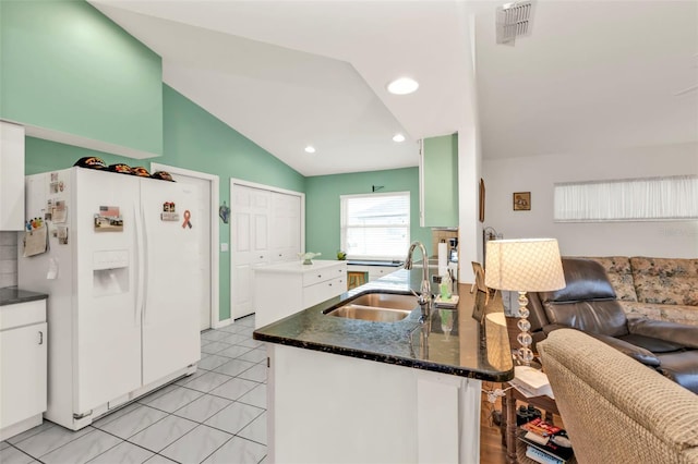 kitchen featuring sink, light tile patterned floors, white cabinetry, white fridge with ice dispenser, and vaulted ceiling