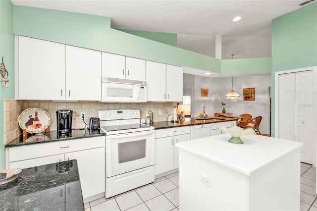 kitchen featuring tasteful backsplash, dark stone countertops, white cabinets, and white appliances