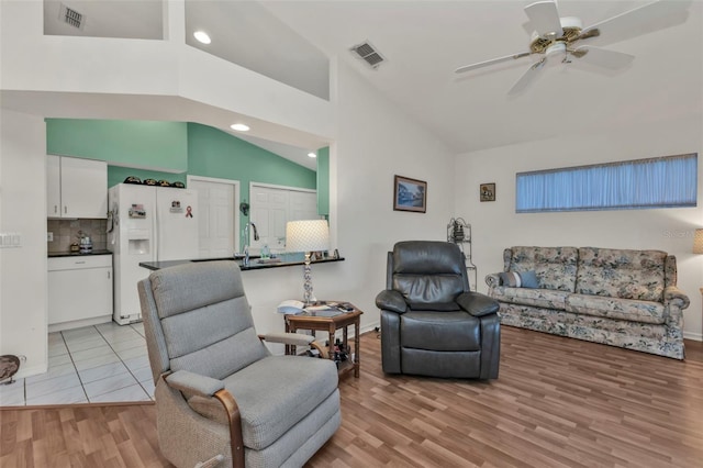 living room featuring sink, high vaulted ceiling, light hardwood / wood-style floors, and ceiling fan