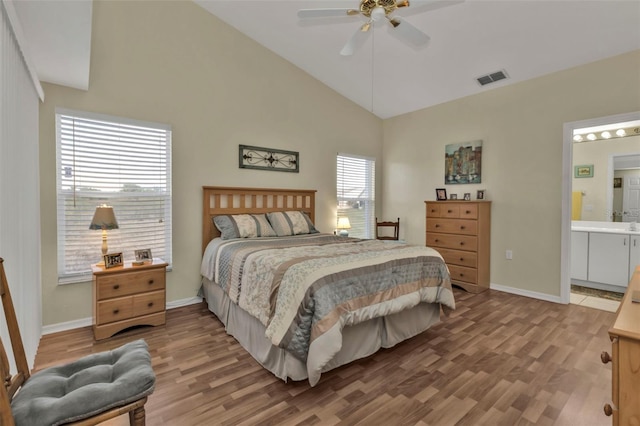 bedroom featuring ceiling fan, ensuite bathroom, high vaulted ceiling, and hardwood / wood-style floors