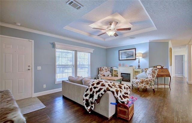 living room featuring dark wood-type flooring, a tray ceiling, a textured ceiling, and crown molding