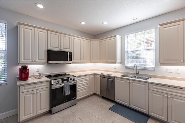 kitchen featuring a healthy amount of sunlight, appliances with stainless steel finishes, sink, and light tile patterned floors