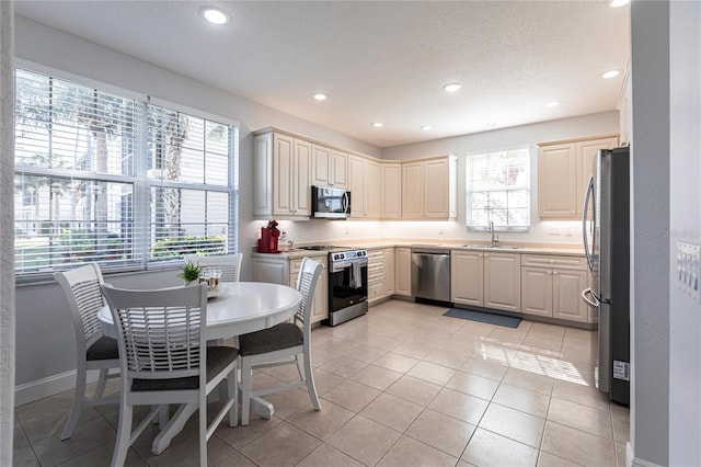 kitchen with sink, light tile patterned floors, a textured ceiling, and appliances with stainless steel finishes