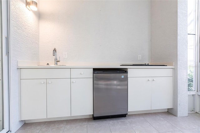 kitchen featuring white cabinetry, sink, light tile patterned floors, and refrigerator