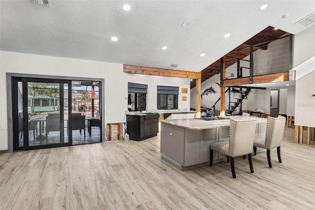 kitchen featuring light stone counters, a kitchen bar, and light wood-type flooring