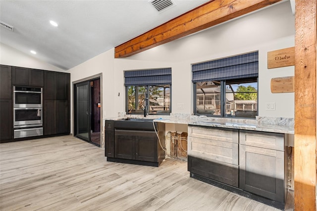 kitchen featuring double oven, sink, vaulted ceiling with beams, light stone countertops, and light hardwood / wood-style flooring