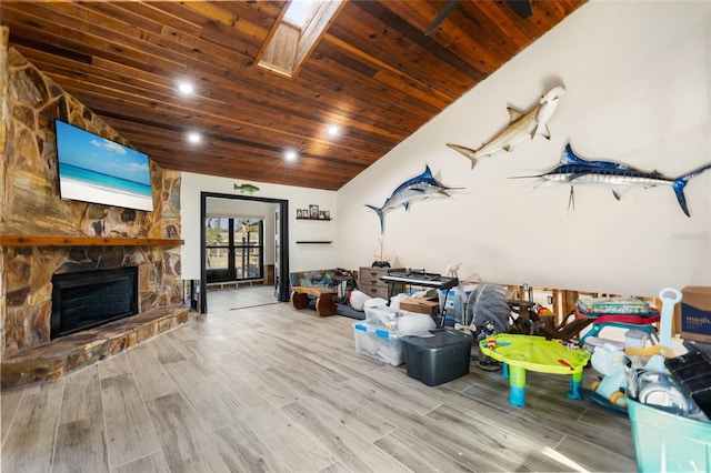 interior space featuring wood ceiling, a fireplace, vaulted ceiling with skylight, and light hardwood / wood-style flooring