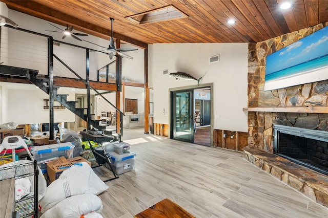 living room with ceiling fan, a fireplace, light wood-type flooring, and wooden ceiling