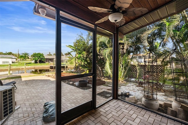 unfurnished sunroom featuring a water view and ceiling fan