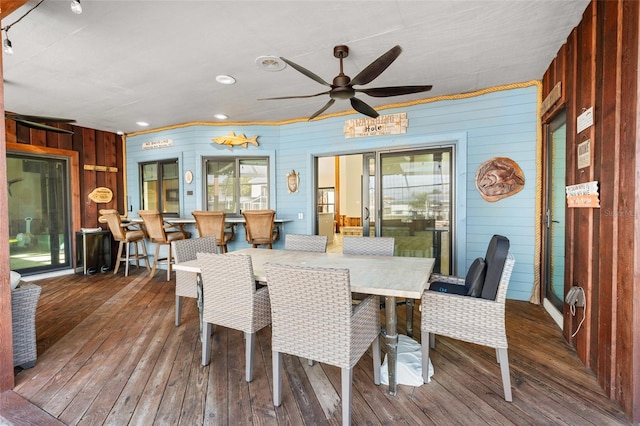 dining area featuring ceiling fan, wooden walls, dark hardwood / wood-style floors, and a wealth of natural light