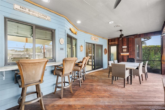 dining area featuring ceiling fan, wooden walls, and hardwood / wood-style floors