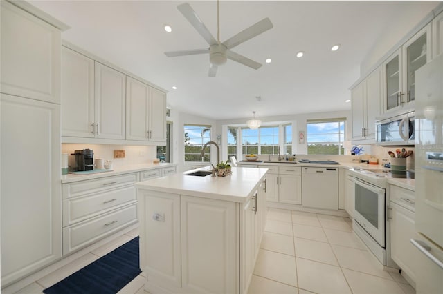 kitchen with sink, white appliances, white cabinets, and a center island with sink