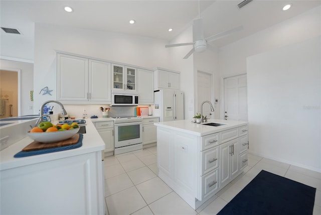 kitchen featuring white cabinetry, sink, white appliances, and an island with sink