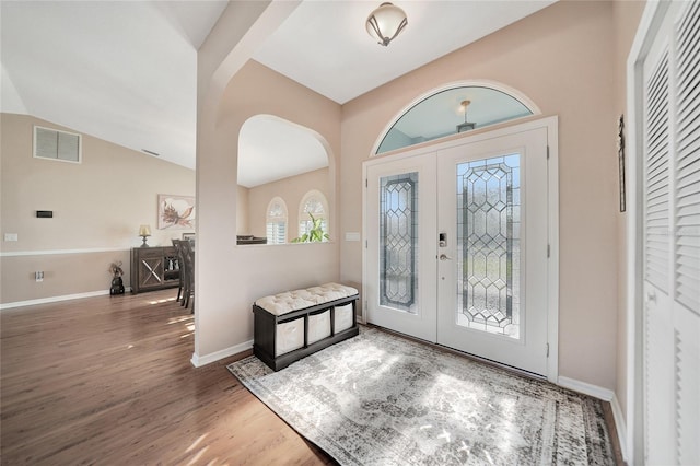 foyer with hardwood / wood-style flooring, vaulted ceiling, and french doors