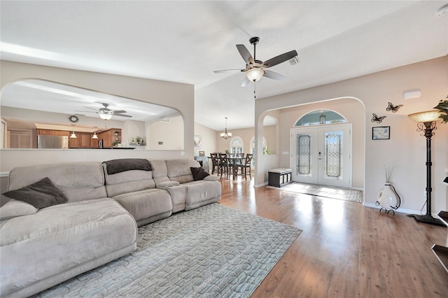 living room featuring wood-type flooring, lofted ceiling, and ceiling fan with notable chandelier