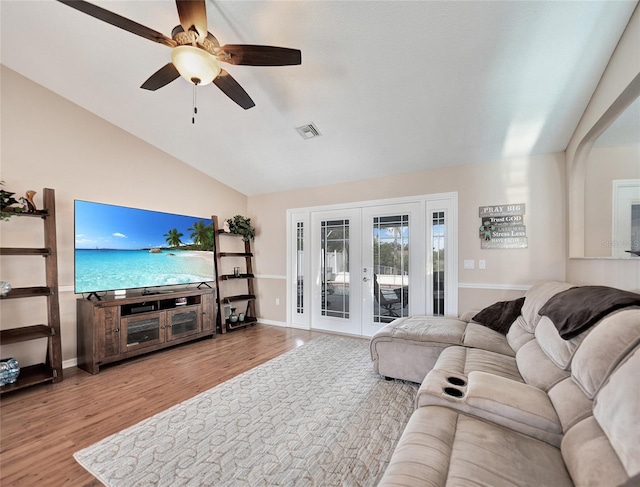 living room with lofted ceiling, french doors, ceiling fan, and light wood-type flooring