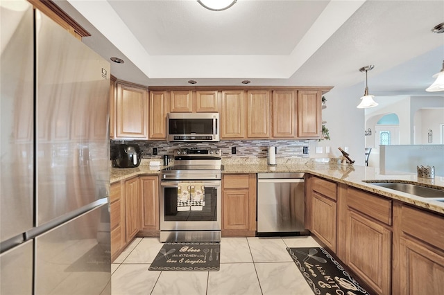 kitchen with tasteful backsplash, hanging light fixtures, a tray ceiling, kitchen peninsula, and stainless steel appliances