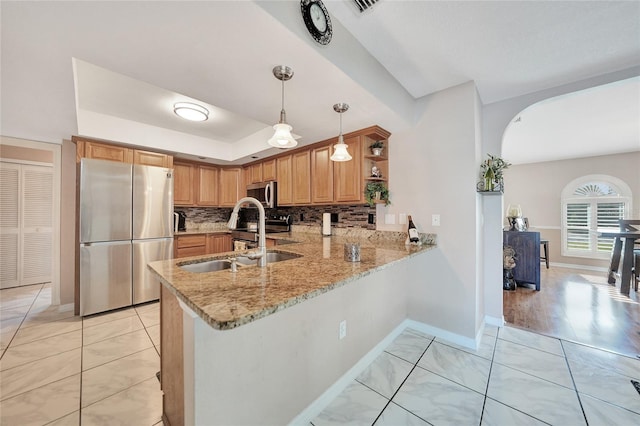 kitchen with appliances with stainless steel finishes, pendant lighting, tasteful backsplash, sink, and kitchen peninsula