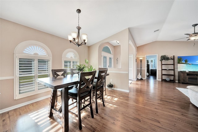 dining space with lofted ceiling, ceiling fan with notable chandelier, and dark hardwood / wood-style flooring